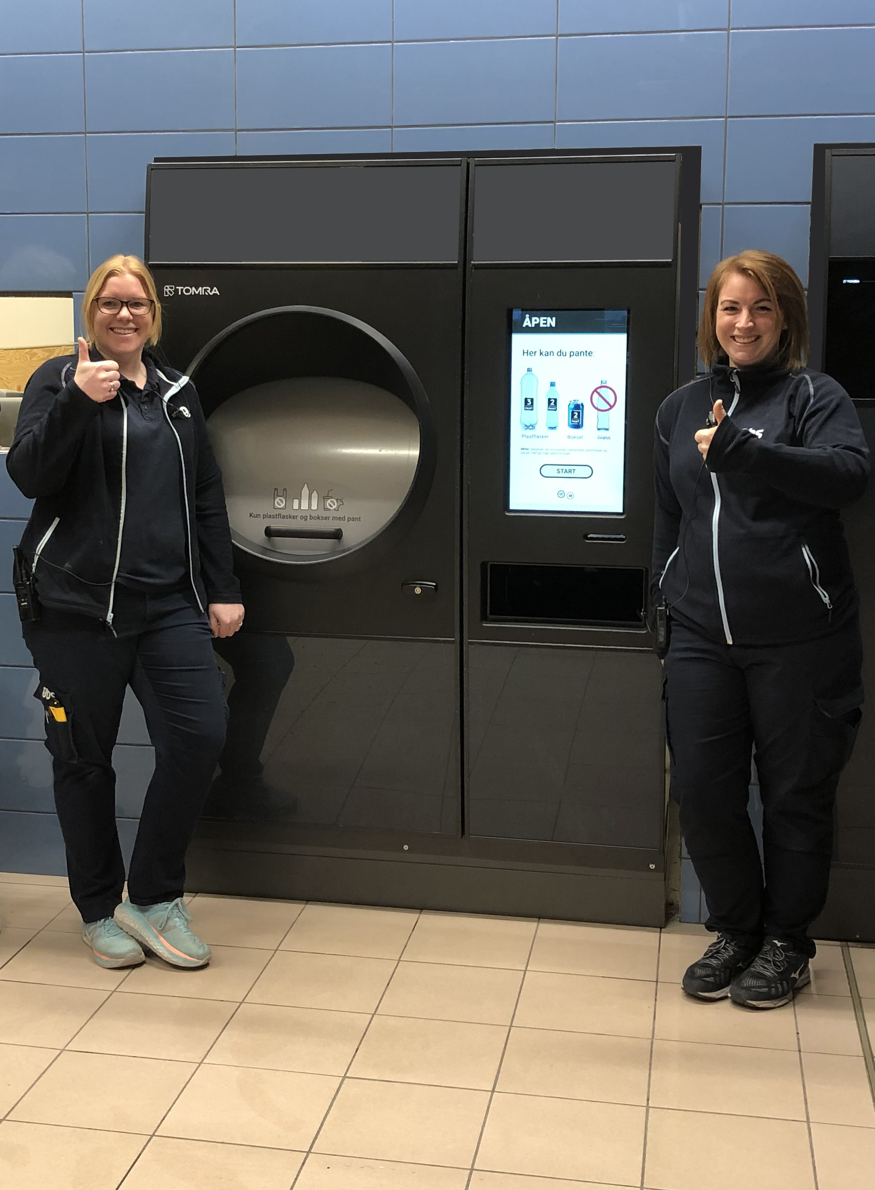 image of two coop staff standing beside a reverse vending machine 