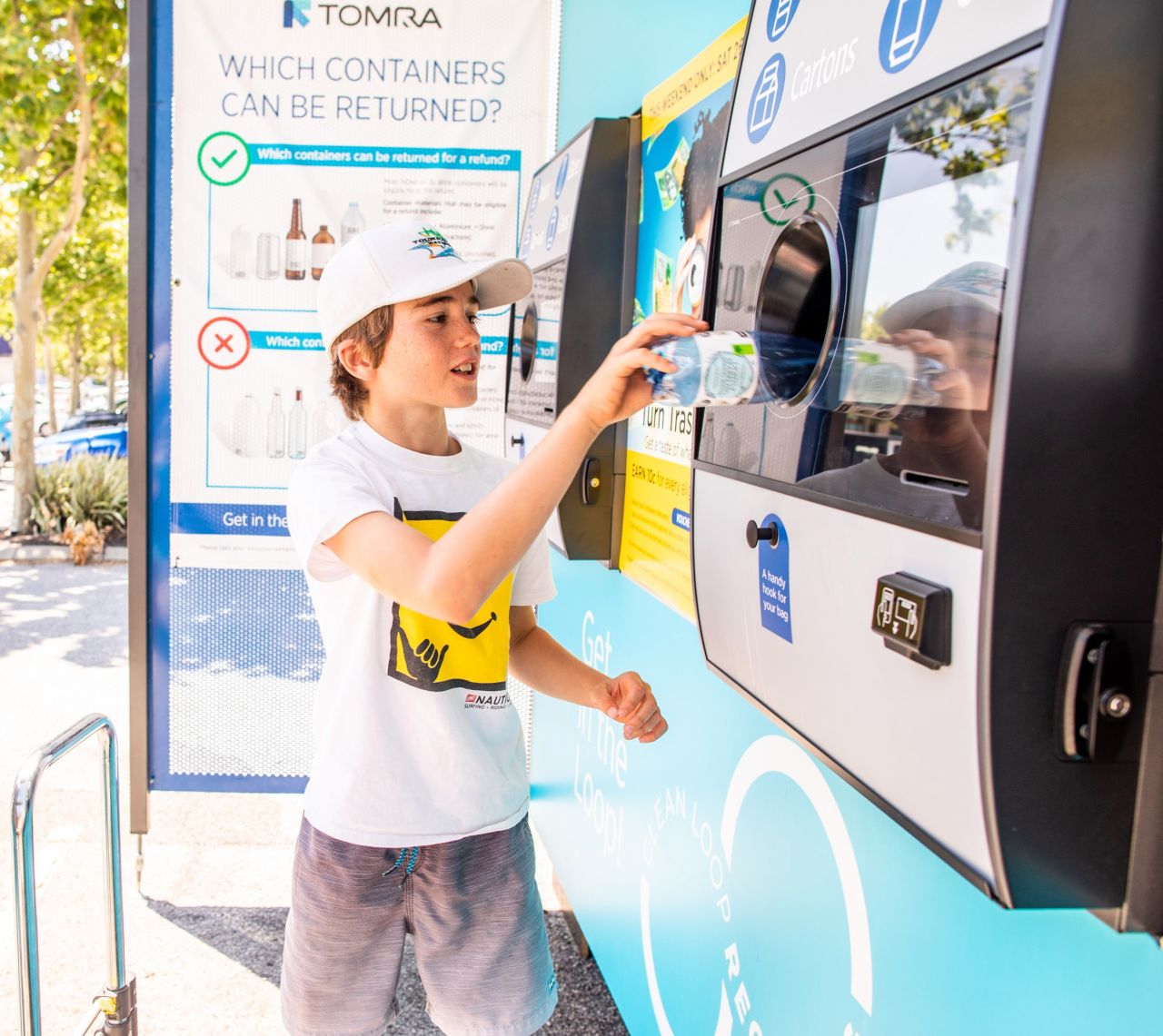 a boy feeding a bottle to reverse vending machine