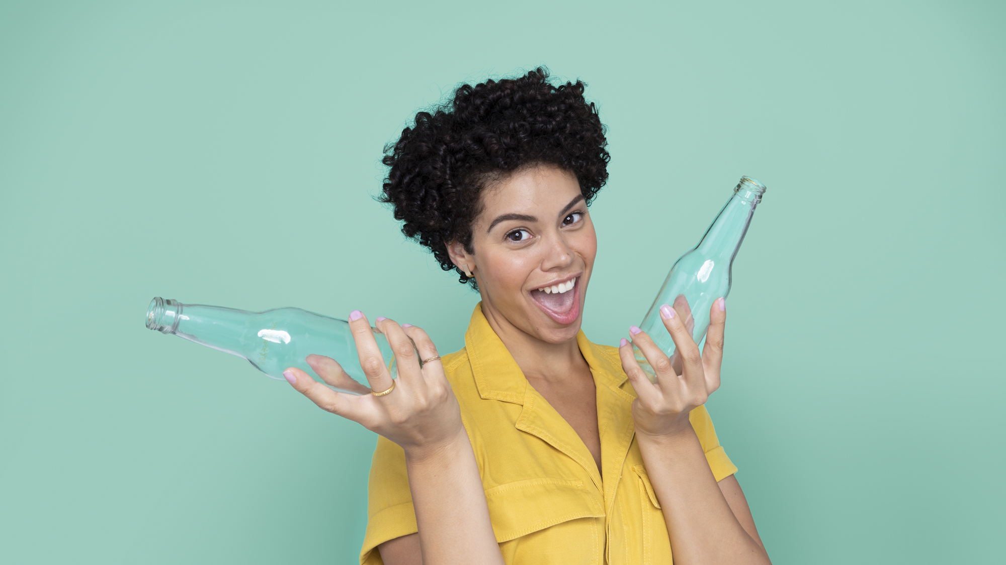 Femme souriante tenant deux bouteilles en verre 