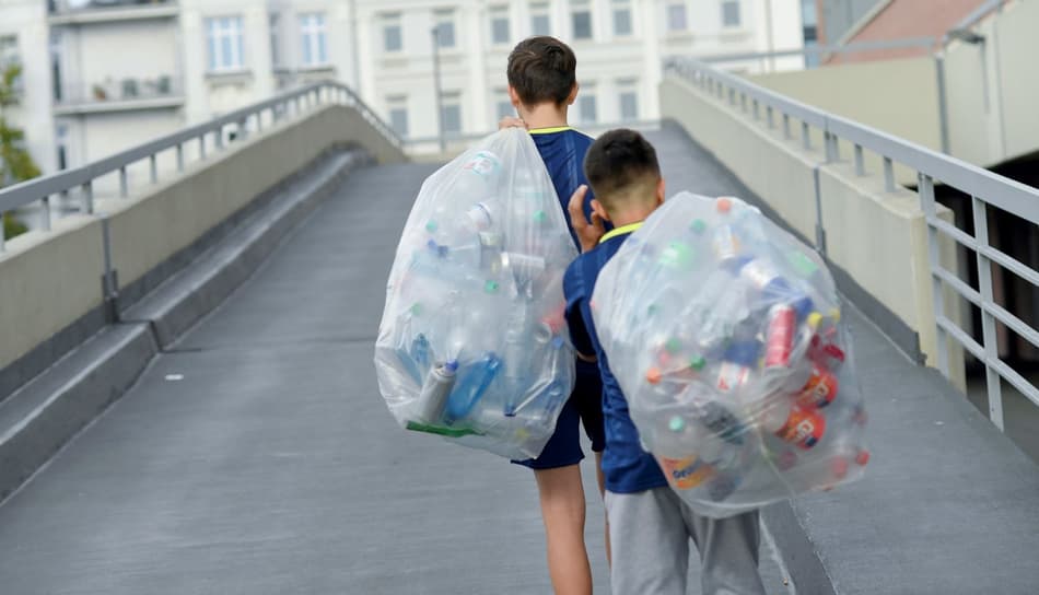 Photo de garçons transportant des sacs remplis de contenants de boisson