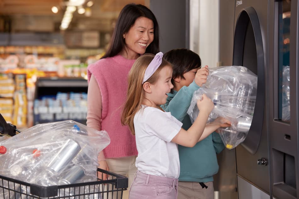 Eine Frau  und ihre Kinder stellen leere Verpackungen in einen TOMRA Leergutrücknahme-Automat