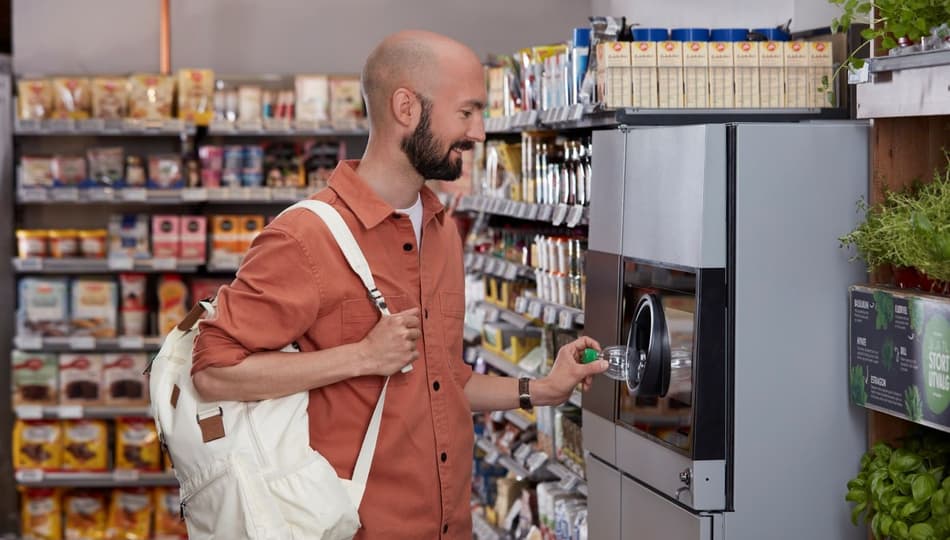 Bild eines Mannes, der Dosen an Leergutrücknahme-Automaten zurückgibt