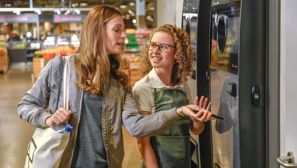 two ladies with a reverse vending machine